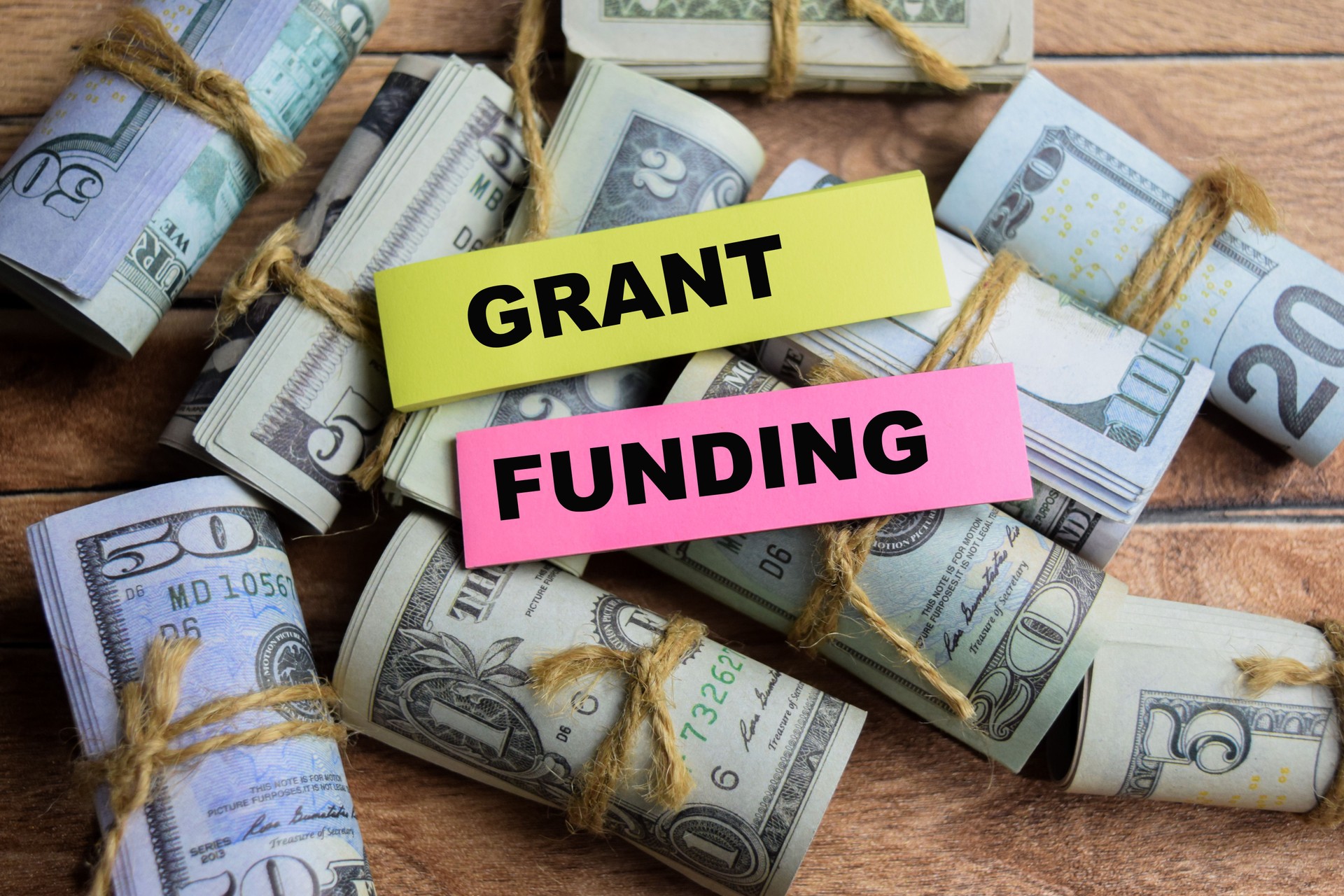 Concept Grant Funding on sticky notes on a wooden table with dollar bills